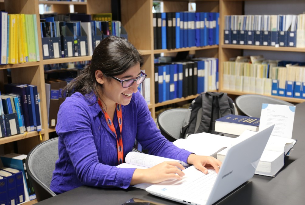 Student studying as laptop with books